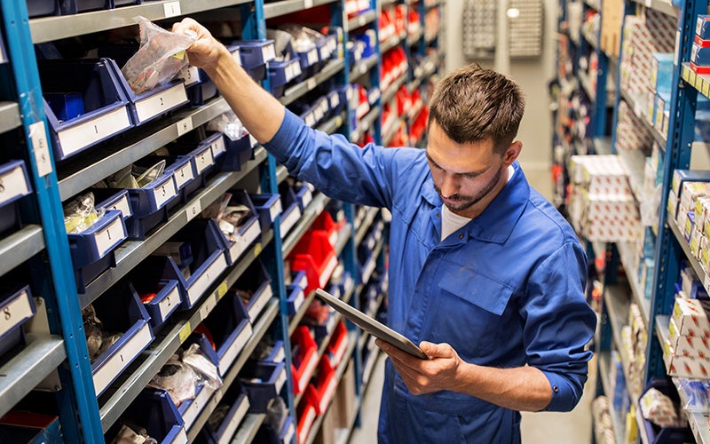 A mechanic collecting parts by list in his hand