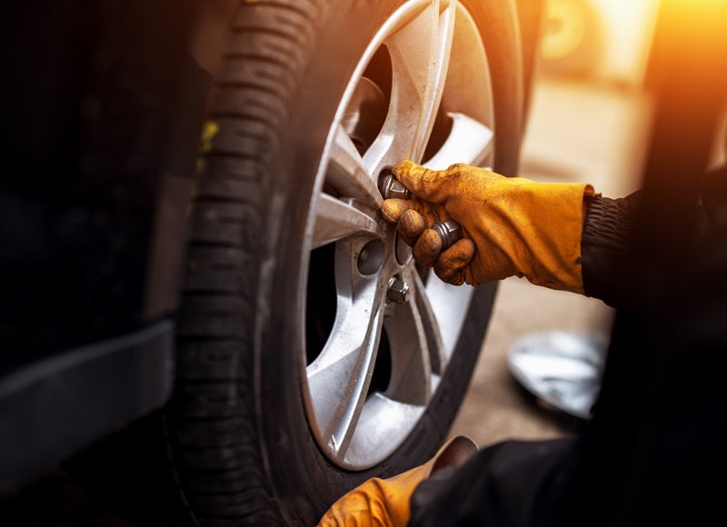 A mechanic fitting a tire into a car